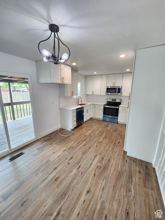 kitchen with light wood-style flooring, visible vents, appliances with stainless steel finishes, and a sink