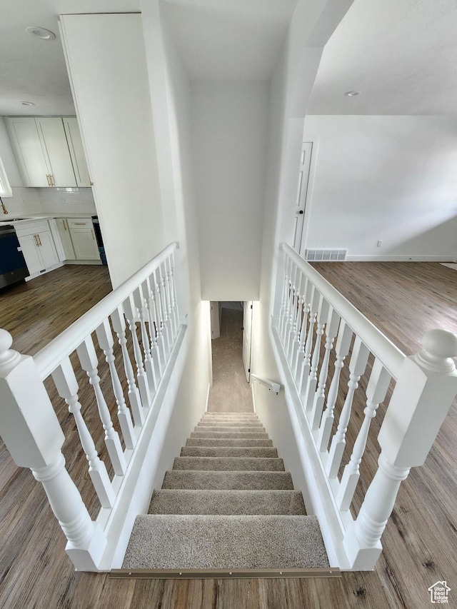stairs with visible vents and wood finished floors