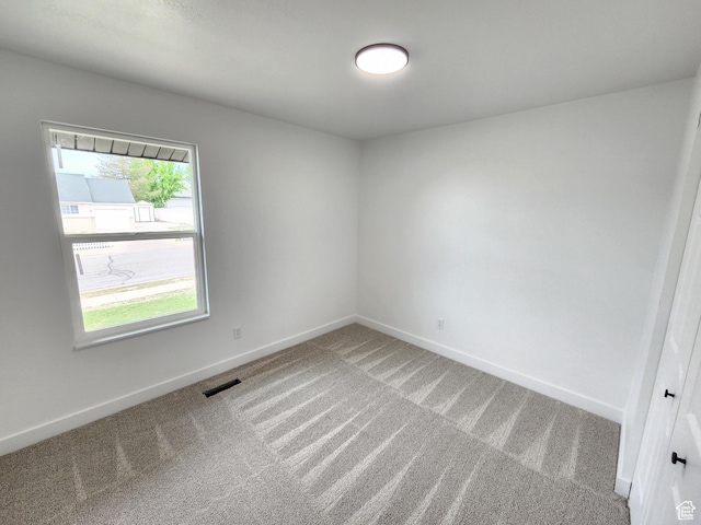 spare room with baseboards, carpet floors, and visible vents