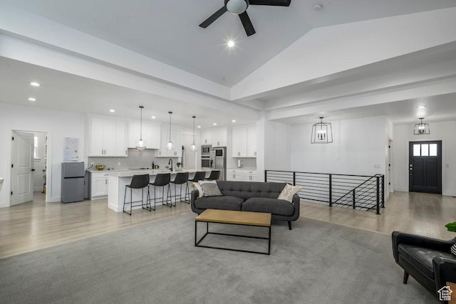 living area with ceiling fan with notable chandelier, vaulted ceiling, recessed lighting, and light wood finished floors