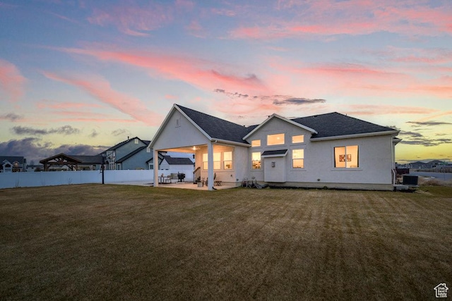 view of front of house featuring a shingled roof, fence, a lawn, cooling unit, and a patio area