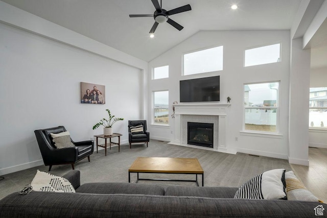 living area featuring a wealth of natural light, a fireplace with flush hearth, high vaulted ceiling, and ceiling fan