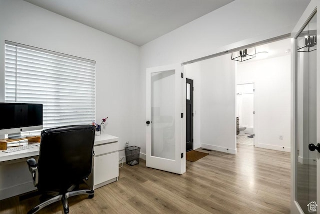 home office with french doors, light wood-type flooring, and baseboards