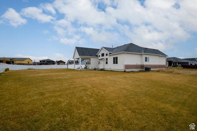 exterior space featuring cooling unit, a lawn, brick siding, and fence