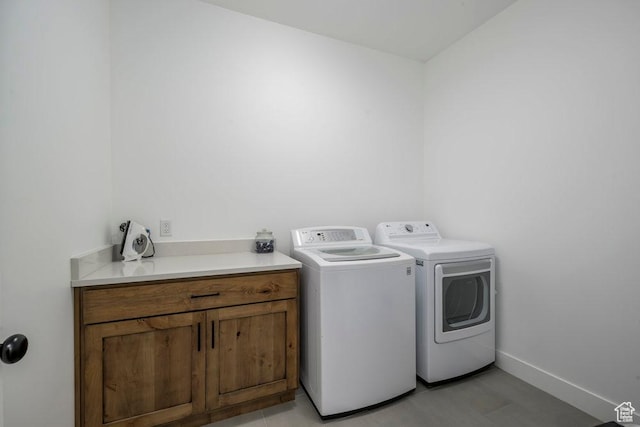 washroom with cabinet space, separate washer and dryer, and baseboards