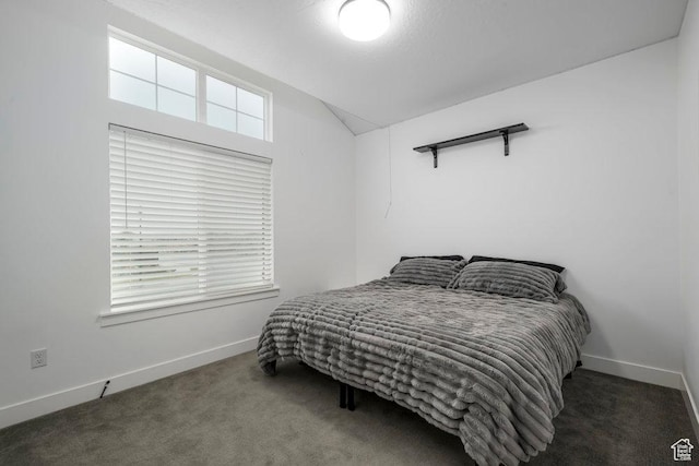 carpeted bedroom featuring baseboards and lofted ceiling