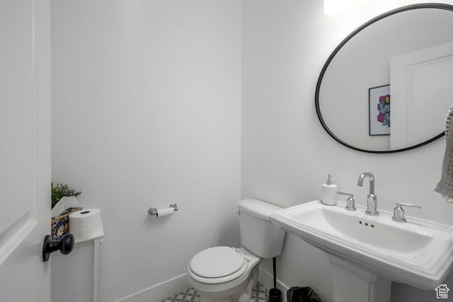 bathroom with toilet, baseboards, and a sink