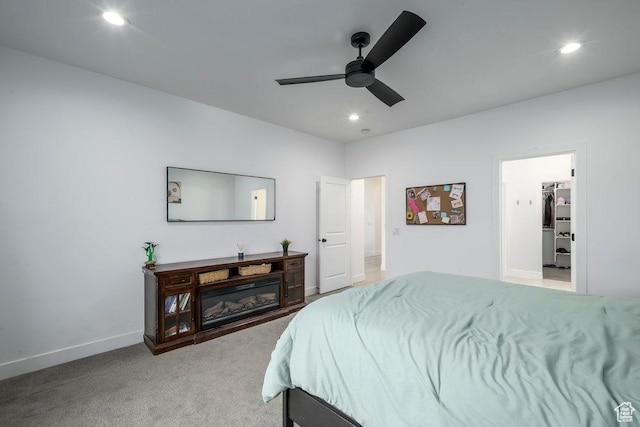 bedroom featuring recessed lighting, baseboards, light colored carpet, and a glass covered fireplace