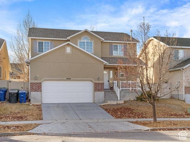 traditional home with stucco siding, fence, covered porch, concrete driveway, and a garage