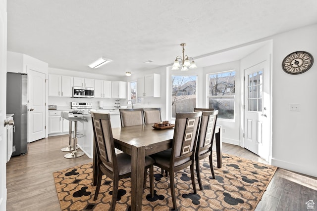 7009 W 7895 S, West Jordan, UT 84081 - dining area featuring a chandelier, baseboards, and light wood-style flooring