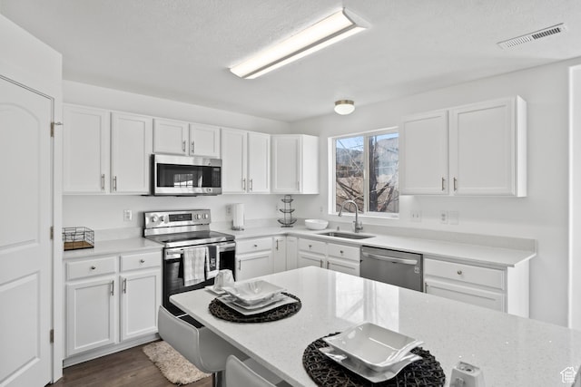 7009 W 7895 S, West Jordan, UT 84081 - kitchen with visible vents, a sink, white cabinets, stainless steel appliances, and dark wood-style flooring
