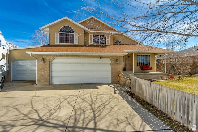 view of front of house with stucco siding, brick siding, a garage, and driveway