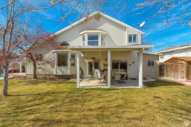 rear view of house featuring a storage unit, a patio, an outbuilding, and a lawn