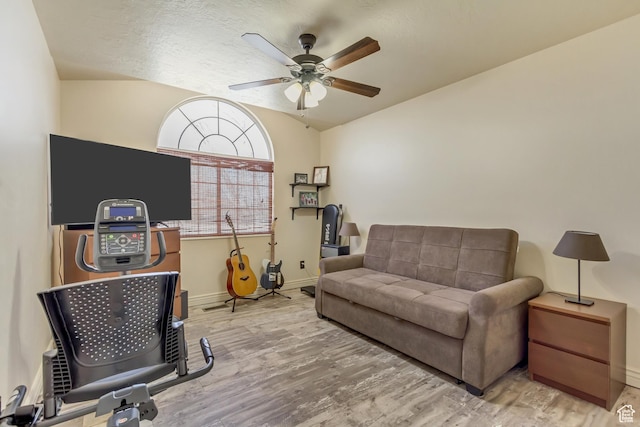 interior space featuring a ceiling fan, vaulted ceiling, baseboards, and wood finished floors