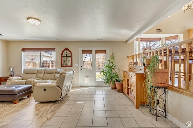 living room featuring a textured ceiling, baseboards, and light tile patterned floors