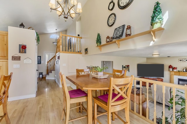 dining area with an inviting chandelier, stairway, light wood-style flooring, and baseboards
