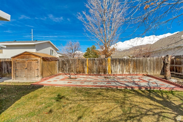 view of yard with an outbuilding, a mountain view, a patio area, a fenced backyard, and a storage unit