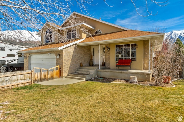 view of front of house featuring covered porch, a mountain view, fence, a front lawn, and brick siding