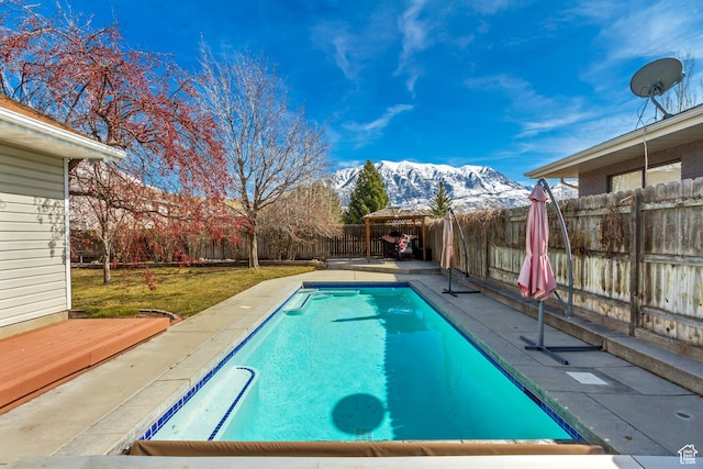 view of swimming pool featuring a gazebo, a yard, a fenced backyard, a fenced in pool, and a deck with mountain view