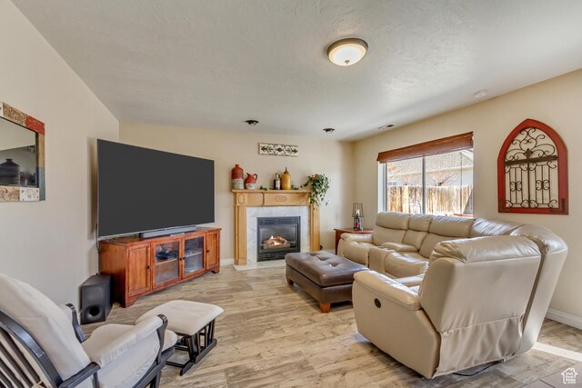 living area featuring light wood-type flooring, a tiled fireplace, and baseboards