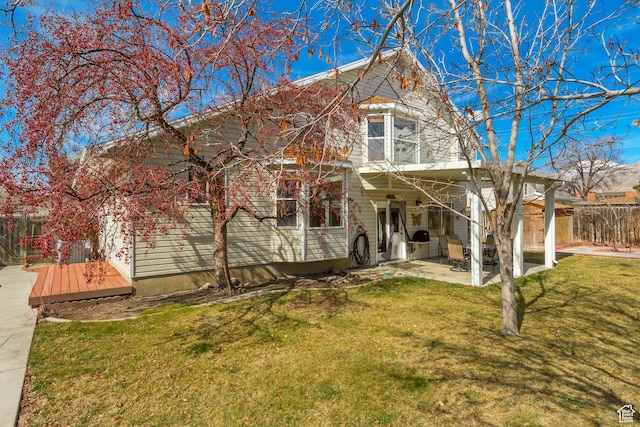 view of front of property with a patio area, a wooden deck, fence, and a front yard