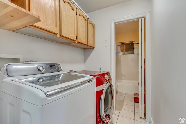 laundry area with independent washer and dryer, light tile patterned flooring, and cabinet space
