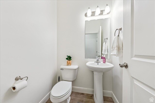 half bathroom with a sink, baseboards, and toilet