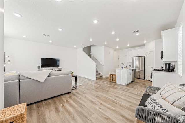 living room with recessed lighting, stairway, visible vents, and light wood-style flooring
