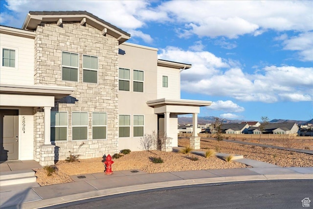 view of front of house with stone siding, a residential view, and stucco siding