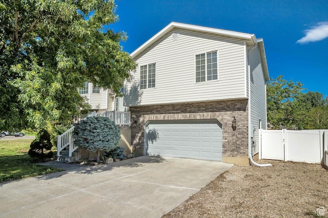 view of home's exterior featuring a garage, brick siding, concrete driveway, and fence