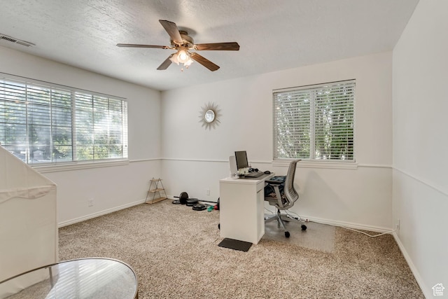 carpeted home office with visible vents, baseboards, a textured ceiling, and a ceiling fan