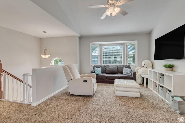 carpeted living room with baseboards, ceiling fan, and vaulted ceiling