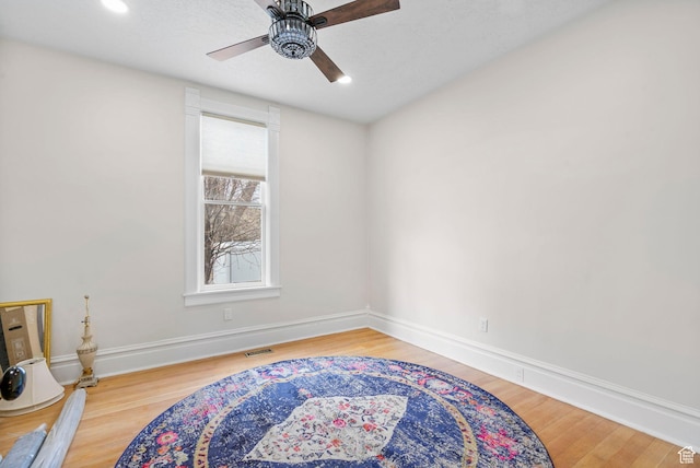 sitting room featuring a ceiling fan, wood finished floors, visible vents, and baseboards