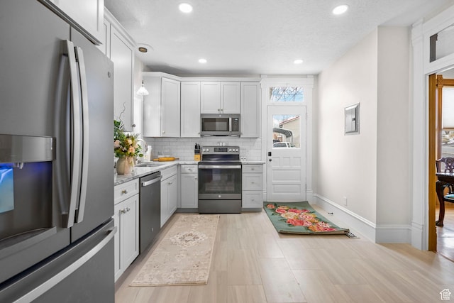kitchen featuring baseboards, recessed lighting, a sink, decorative backsplash, and stainless steel appliances
