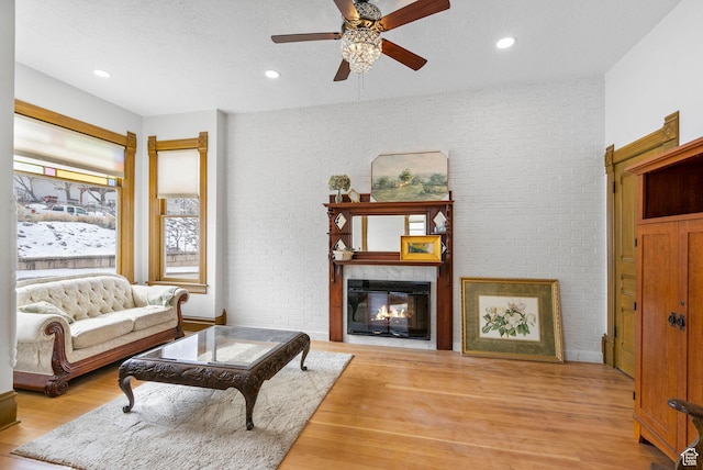 living area featuring a glass covered fireplace, brick wall, and wood finished floors