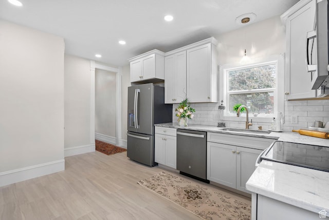 kitchen with light stone counters, backsplash, appliances with stainless steel finishes, and a sink