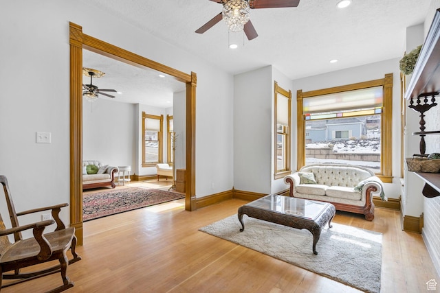 living room with a ceiling fan, baseboards, recessed lighting, a textured ceiling, and light wood-type flooring