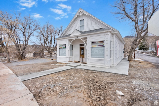 victorian home featuring roof with shingles and covered porch