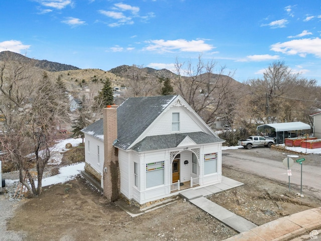 view of front of property with a mountain view, roof with shingles, and a chimney