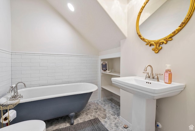 bathroom featuring a sink, toilet, lofted ceiling, and a freestanding tub