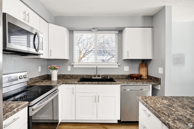 1170 N 730 E, Logan, UT 84341 - kitchen featuring a sink, stainless steel appliances, white cabinets, light wood-style floors, and a textured ceiling