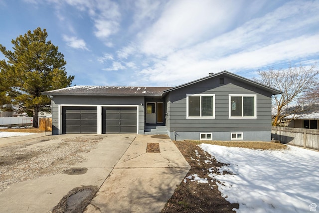ranch-style home with concrete driveway, an attached garage, and fence