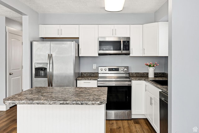 1170 N 730 E, Logan, UT 84341 - kitchen featuring dark wood finished floors, stainless steel appliances, white cabinets, a textured ceiling, and a center island