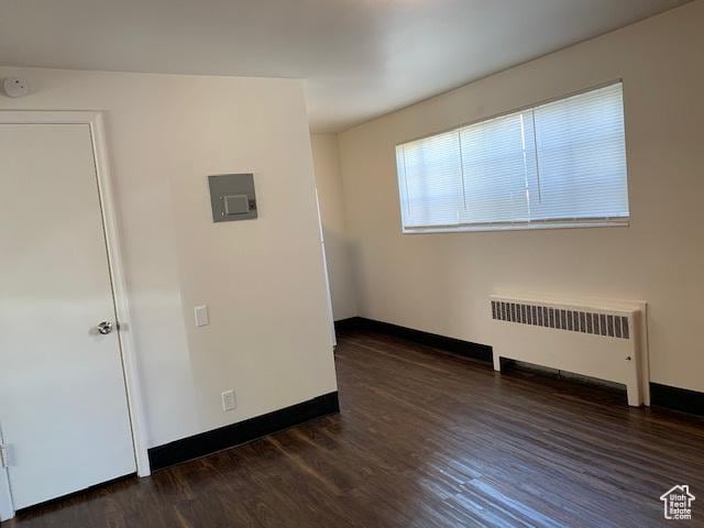 unfurnished room featuring radiator heating unit, baseboards, and wood finished floors
