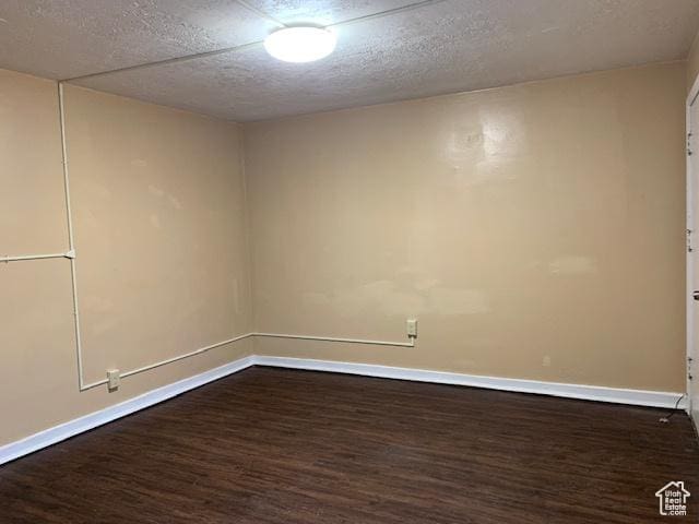 spare room featuring baseboards, a textured ceiling, and dark wood-style flooring