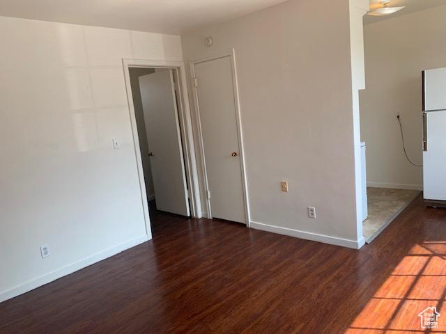 unfurnished room featuring wood finished floors, baseboards, and ornate columns