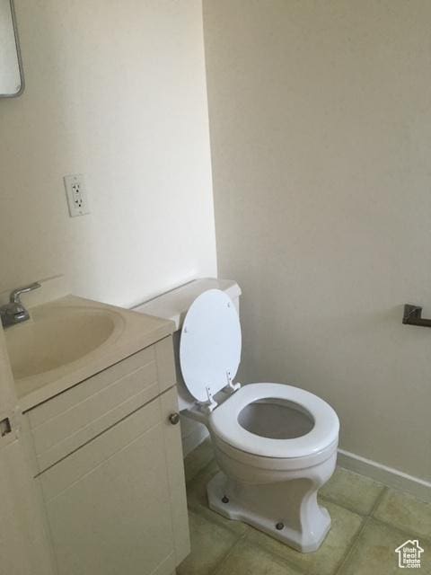 bathroom with baseboards, toilet, vanity, and tile patterned flooring