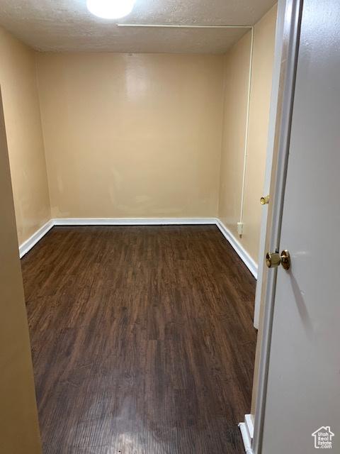 unfurnished room featuring baseboards, a textured ceiling, and dark wood-style flooring