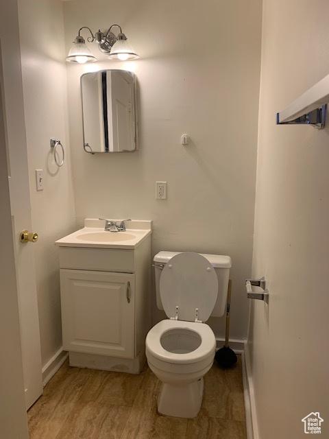 bathroom with vanity, toilet, wood finished floors, and baseboards