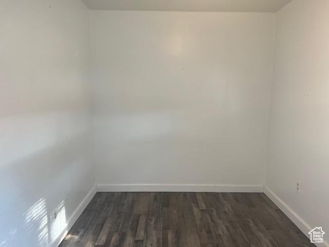 unfurnished room featuring baseboards and dark wood-style flooring
